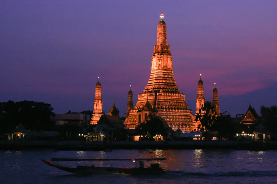 Imponente silueta del templo Wat Arun iluminada al atardecer sobre el río Chao Phraya en Bangkok, Tailandia.