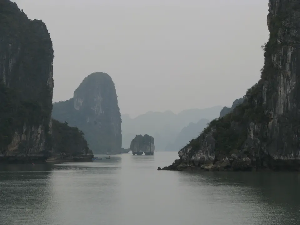 Islotes kársticos de piedra caliza y barcos tradicionales navegando por las aguas esmeralda de la Bahía de Ha Long, Vietnam.