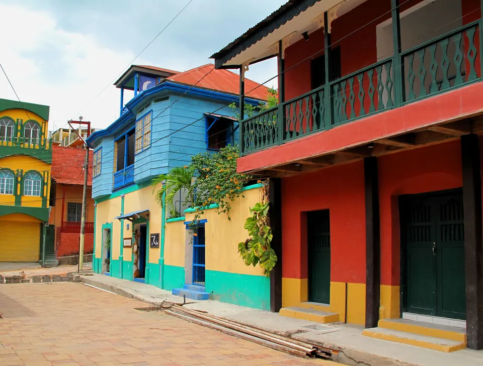 Callejón adoquinado con pintorescas casas de colores pasteles, faroles y balcones floridos en la Isla de Flores.