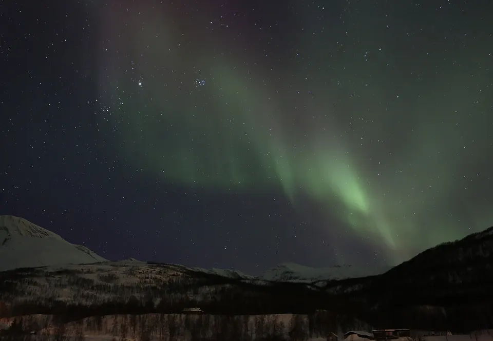 Espirales verdes de aurora boreal sobre las cumbres nevadas y tiendas lavvu sami en Tromsø.
