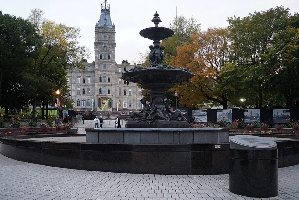 La monumental fuente Fontaine de Tourny iluminada frente a la fachada del Hôtel du Parlement de Québec.