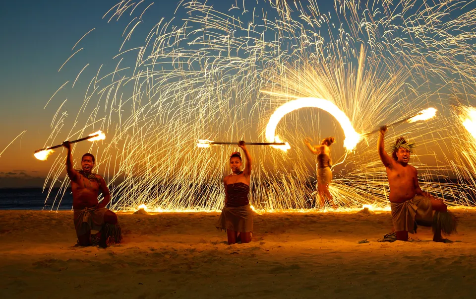 Bailarines fiyianos ejecutando un espectáculo de malabares de fuego nocturno en la playa de Natadola.