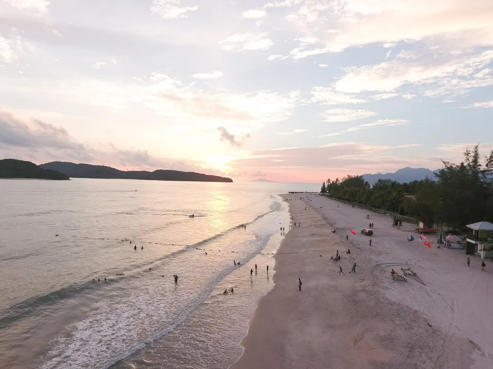 Extensa franja de arena blanca y palmeras bañadas por el mar de Andamán al atardecer en Pantai Cenang.