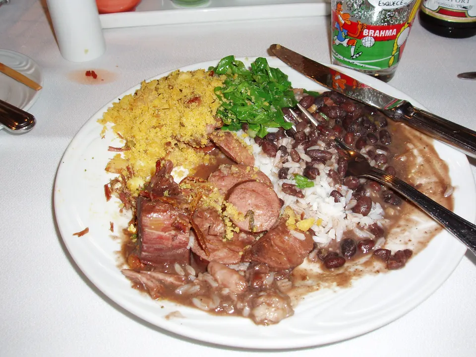 Tradicional feijoada brasileña con frijoles negros, carnes de cerdo, arroz blanco, farofa, couve y naranja.