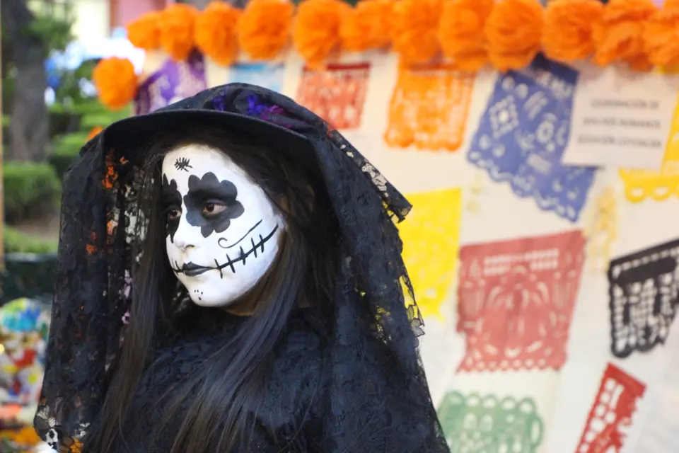 Niña disfrazada de catrina junto a ofrenda de día de muertos en la Celebración del día de muertos que se llevó a cabo de en mexico