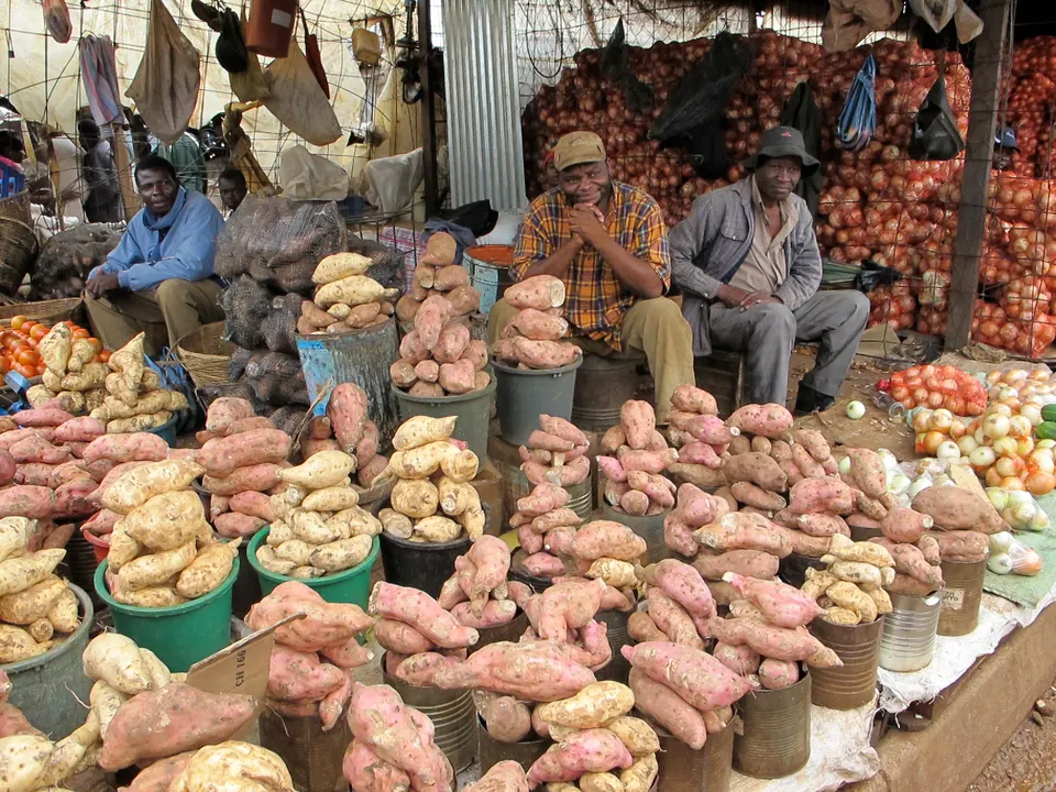 Animado ambiente popular de venta de verduras frescas y artesanías en el mercado Mbare Musika de Harare.
