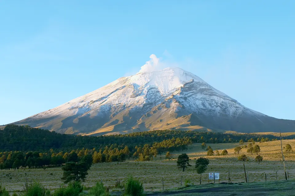 Silueta nevada del volcán Popocatépetl alzándose sobre el valle de Puebla.