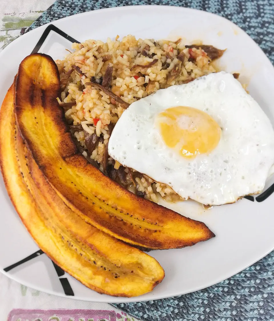 Plato tradicional de majadito cruceño con arroz tostado, charque de res, plátano frito y huevo frito.