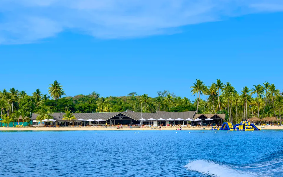 Orilla de arena blanca y aguas transparentes con palmeras en la isla turística de Malolo Lailai.
