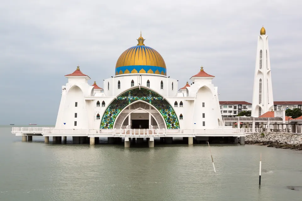La mezquita flotante Masjid Selat Melaka suspendida sobre pilotes en las aguas del estrecho durante la puesta de sol.