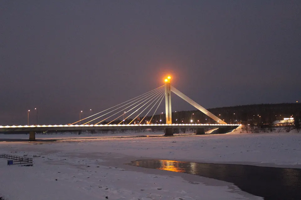 Pilón central con llamas doradas del puente Jätkänkynttilä sobre el caudaloso río Kemijoki.