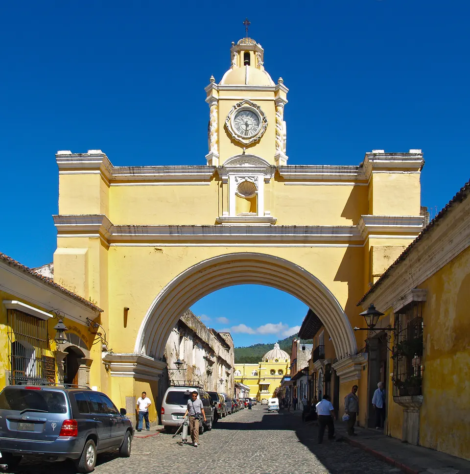 Calle adoquinada y fachada amarilla del Arco de Santa Catalina en Antigua Guatemala.