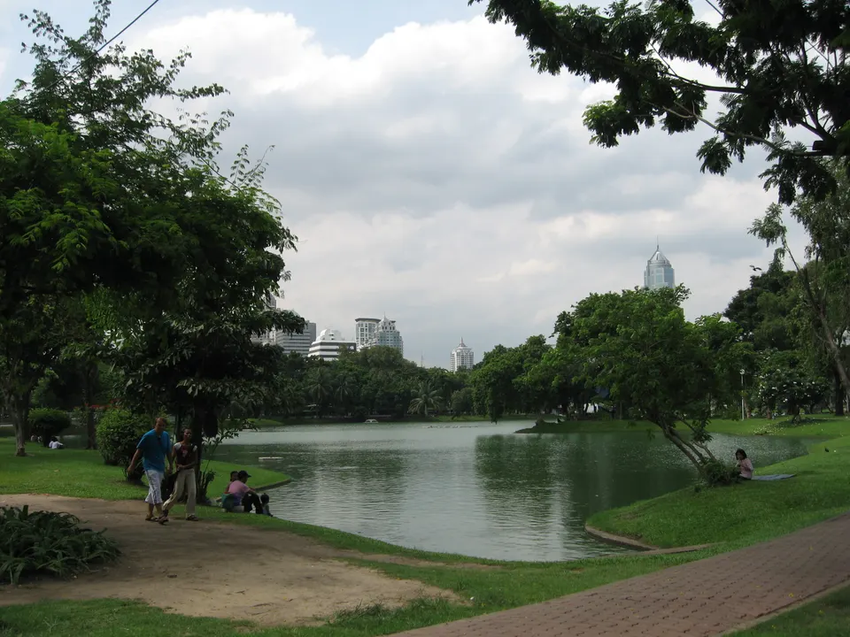 Lago sereno y vegetación del Parque Lumphini contrastando con los rascacielos de Bangkok.