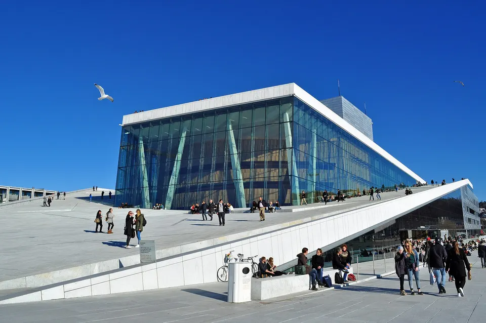 Visitantes caminando por la cubierta inclinada de mármol blanco de Carrara de la Ópera de Oslo.