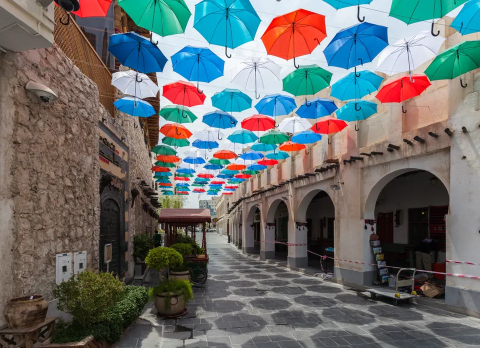 Callejón tradicional del zoco Souq Waqif en Doha explorado por turistas durante una escala stopover.