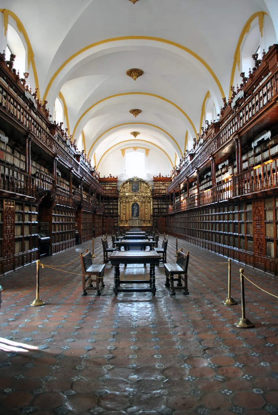 Estanterías de cedro tallado de tres niveles y retablo dorado de la Biblioteca Palafoxiana en Puebla.