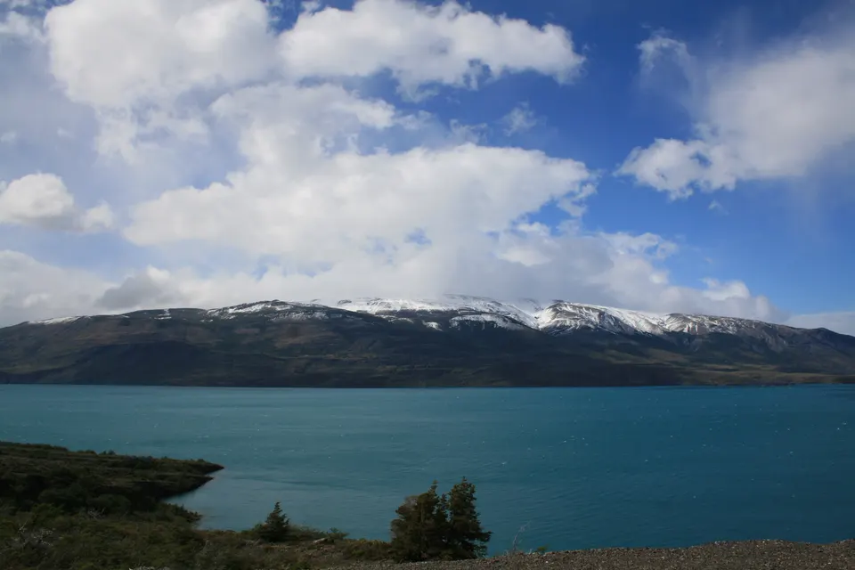 Espejo de aguas turquesas y puente del lago Pehoé con las cumbres nevadas del macizo Paine de fondo
