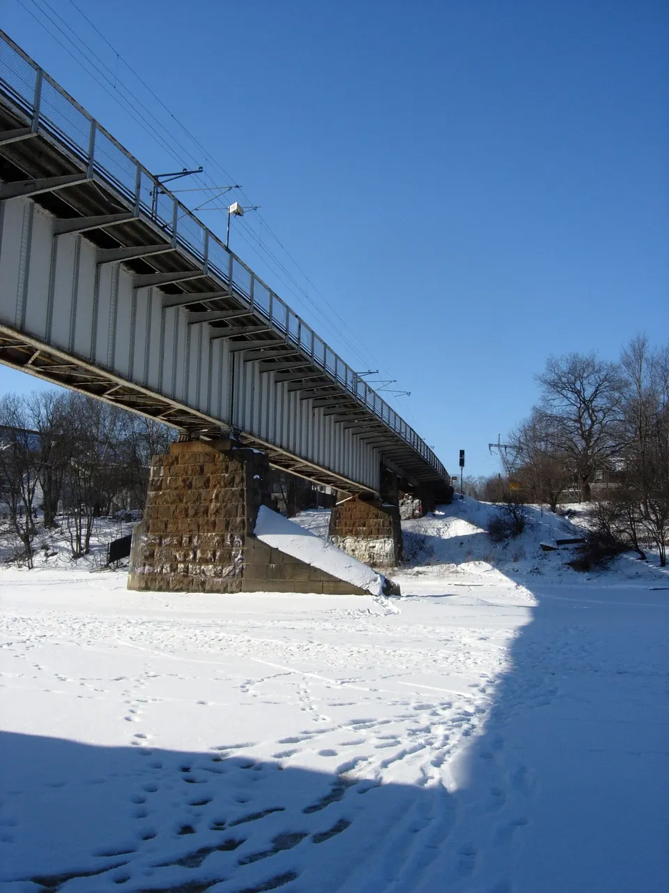 Ribera arbolada del río Aura en Turku con barcos tradicionales de madera reconvertidos en restaurantes.