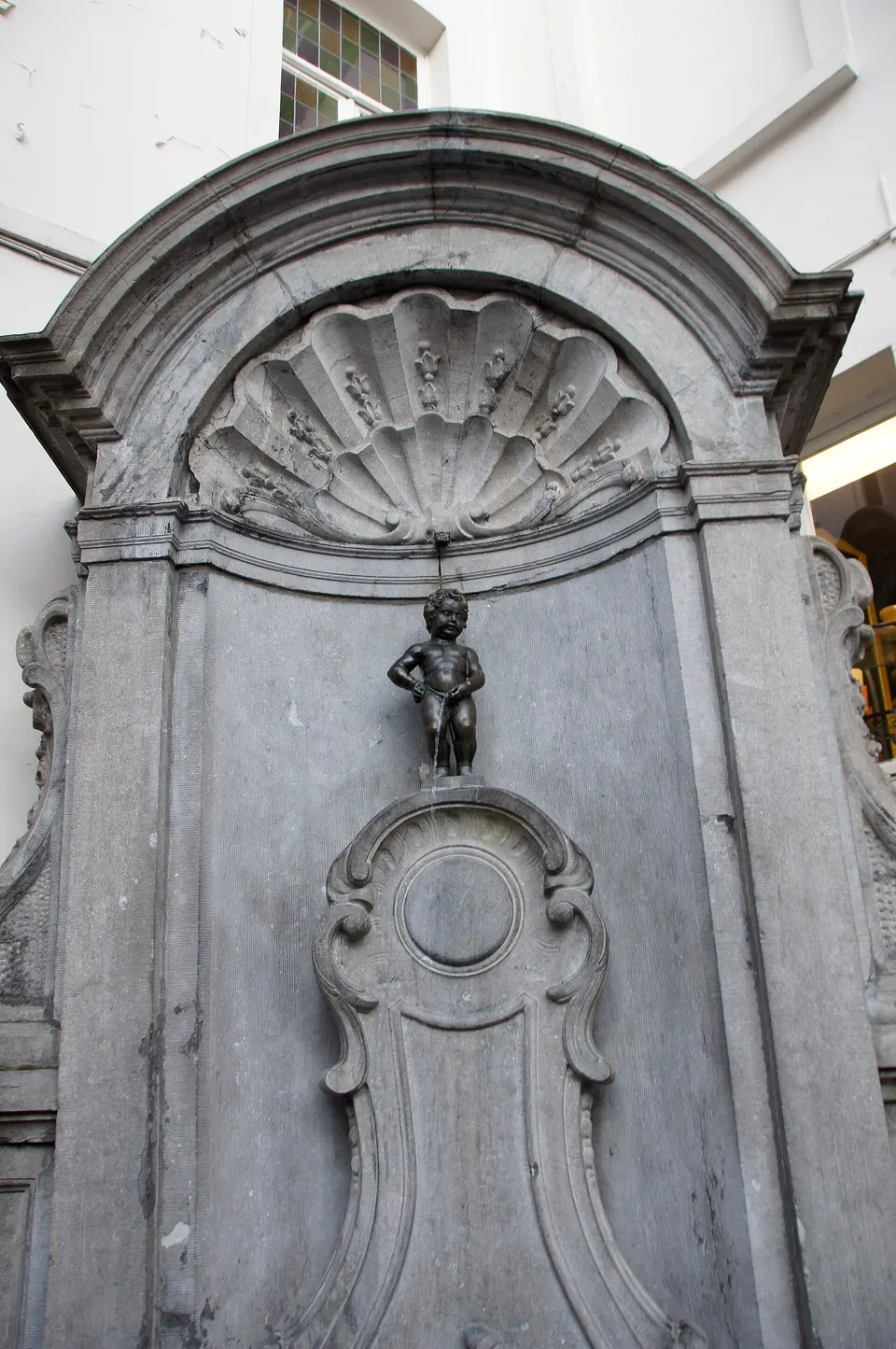 La pequeña estatua de bronce del Manneken Pis en su fuente de la calle de l'Étuve, en Bruselas.