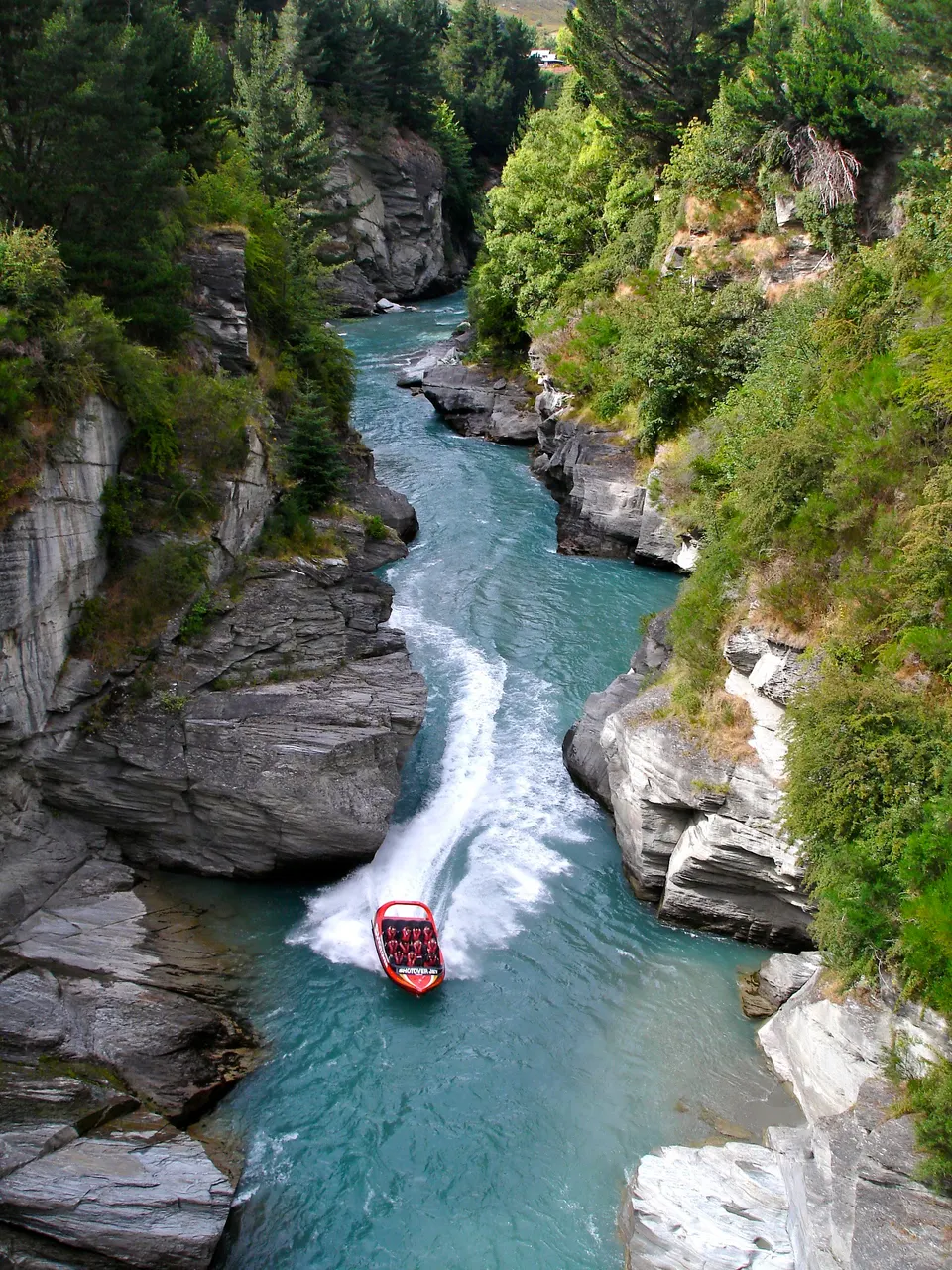 Lancha rápida Shotover Jet surcando a toda velocidad las estrechas gargantas rocosas del río Shotover.