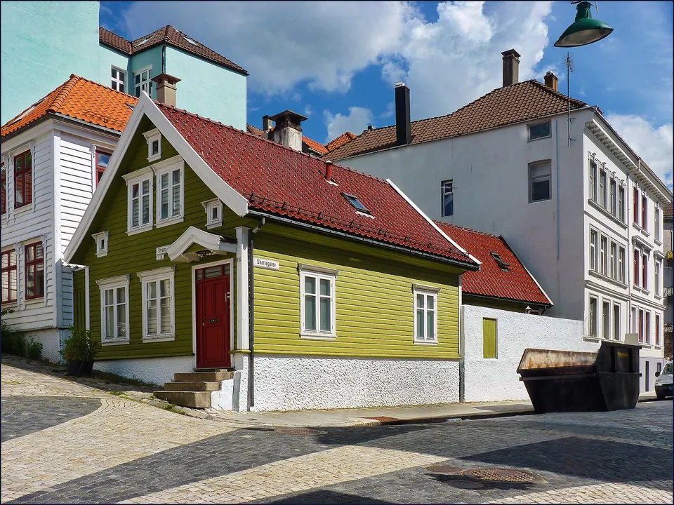 Callejón empedrado flanqueado por pintorescas casas blancas de madera en la península de Nordnes.