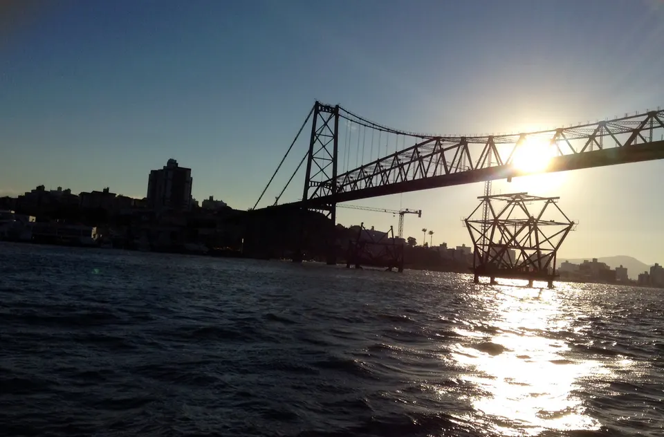El histórico puente colgante Hercílio Luz iluminado sobre la bahía norte de Florianópolis al atardecer.