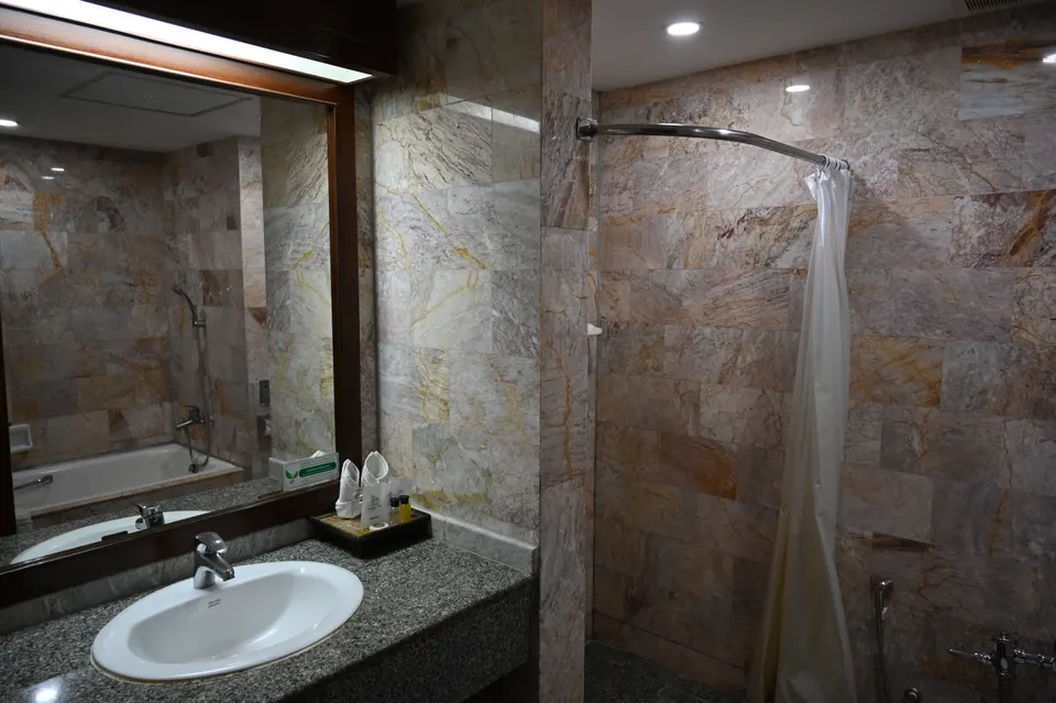 Cuarto de baño de hotel con encimera de granito, toallas y amenities de cortesía.