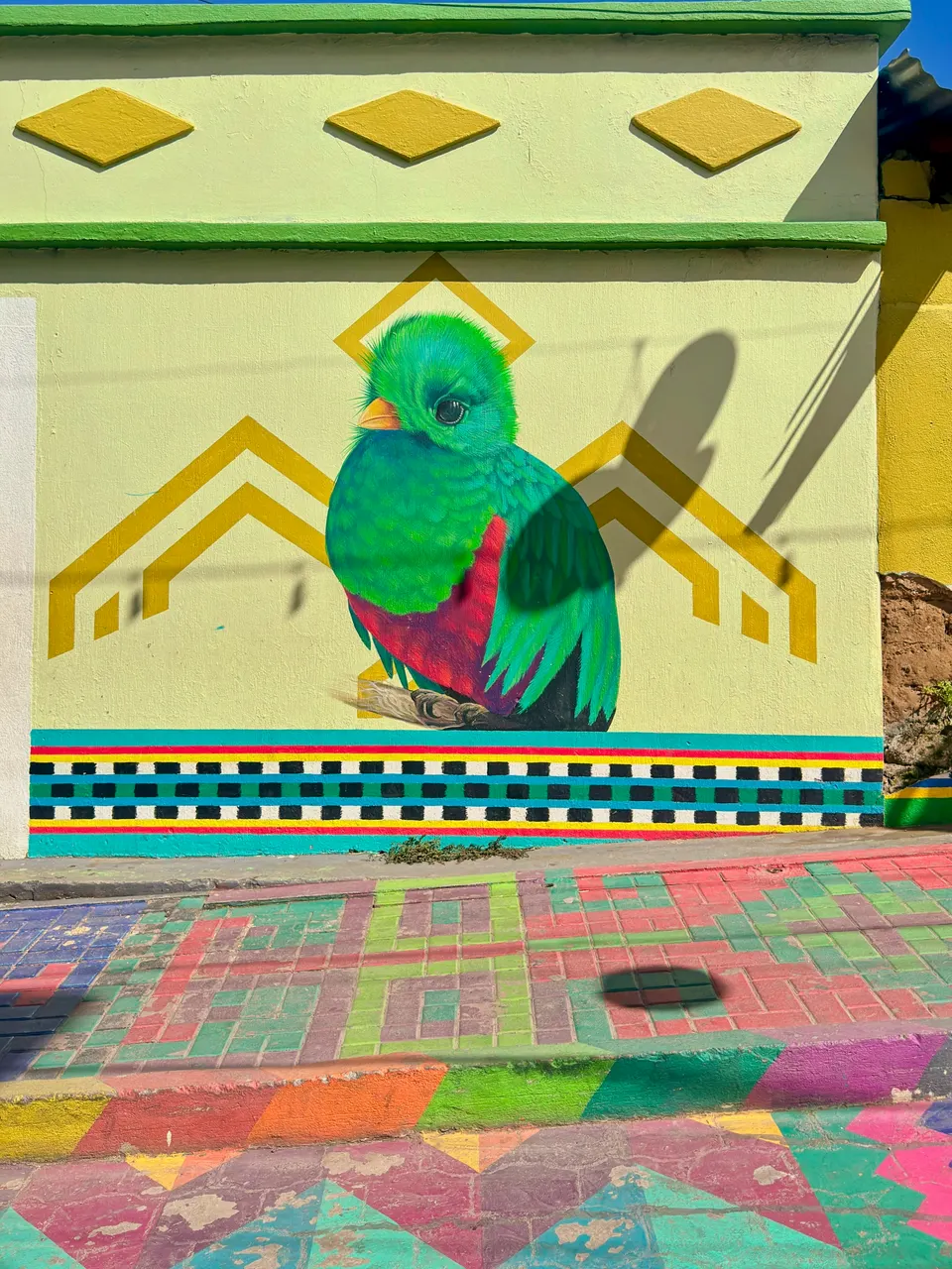 Mural artístico al aire libre en San Juan La Laguna representando un quetzal y los telares tz'utujiles.