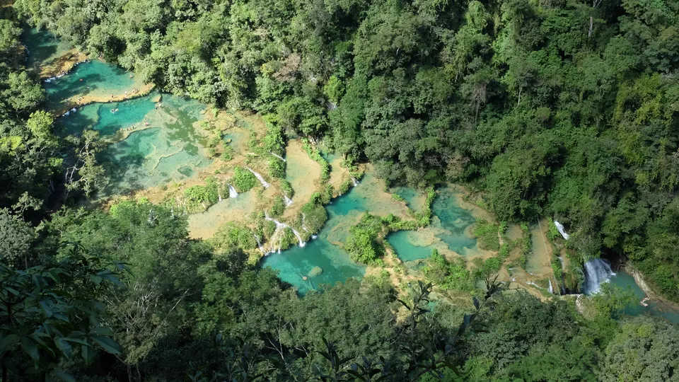 Pozas escalonadas de agua turquesa sobre puente de piedra caliza en Semuc Champey, Alta Verapaz.