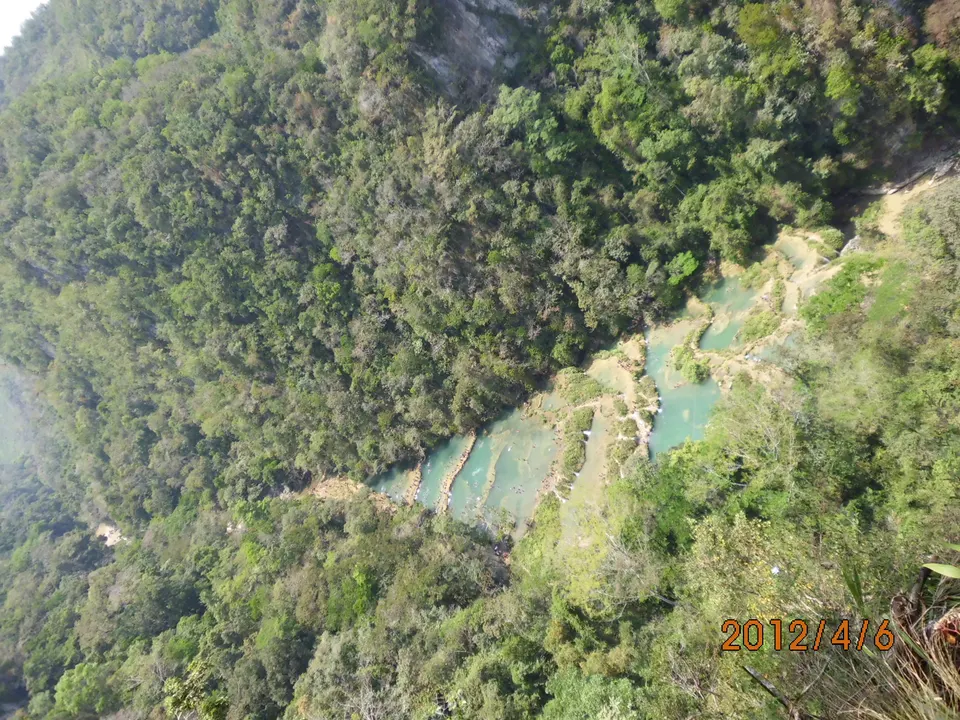 Detalle de los diques de travertino y el agua transparente de las pozas de Semuc Champey rodeadas de bosque tropical.