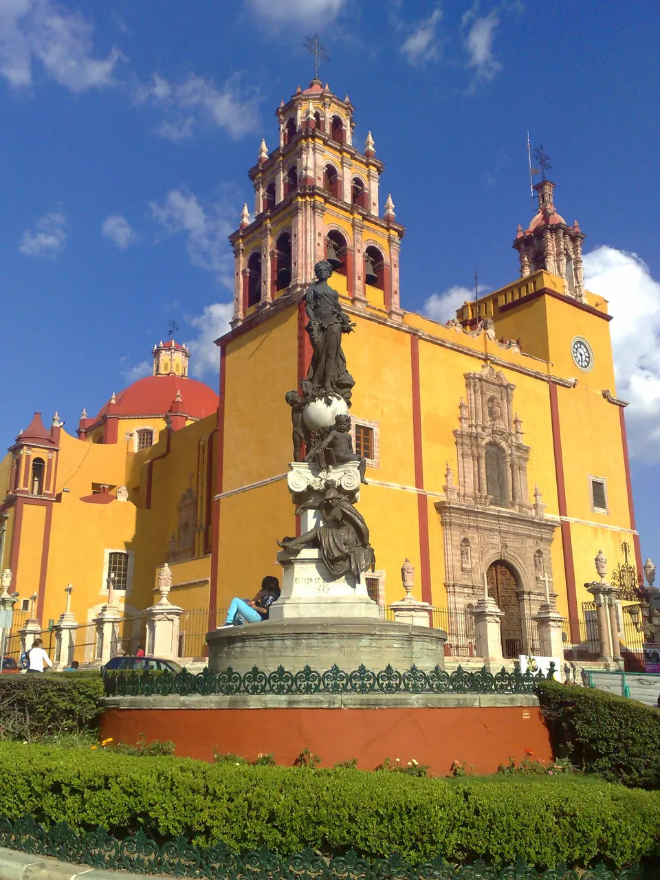 Fachada de cantera amarilla y detalles rojos de la Basílica de Nuestra Señora de Guanajuato en la Plaza de la Paz.