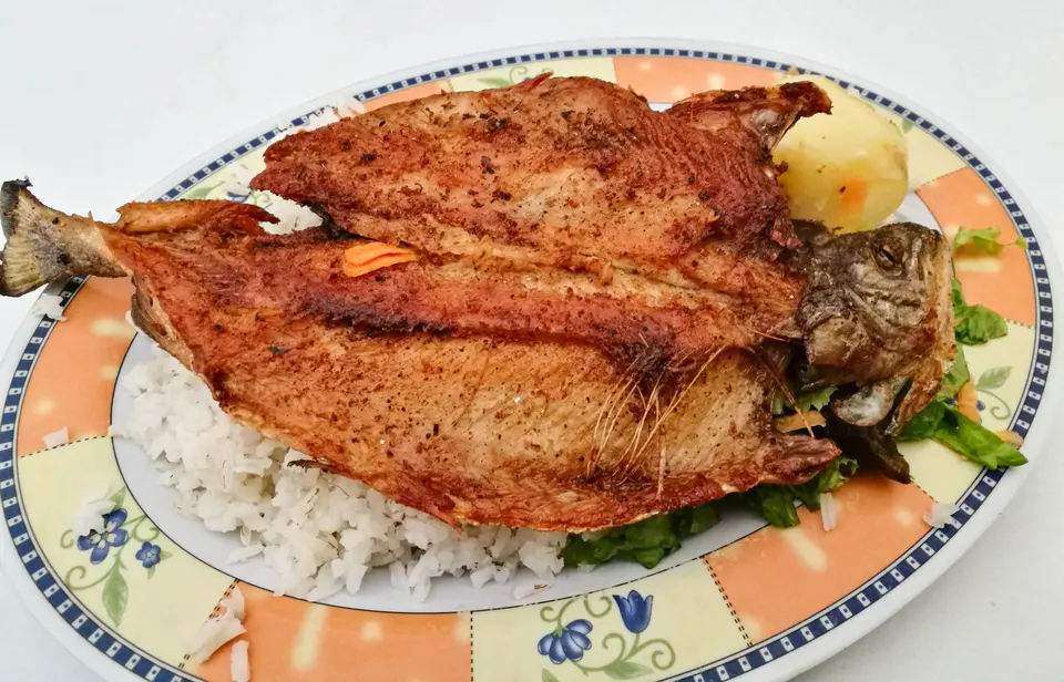 Plato servido de trucha dorada a la plancha recién pescada en el Lago Titicaca acompañada de papas doradas y ensalada