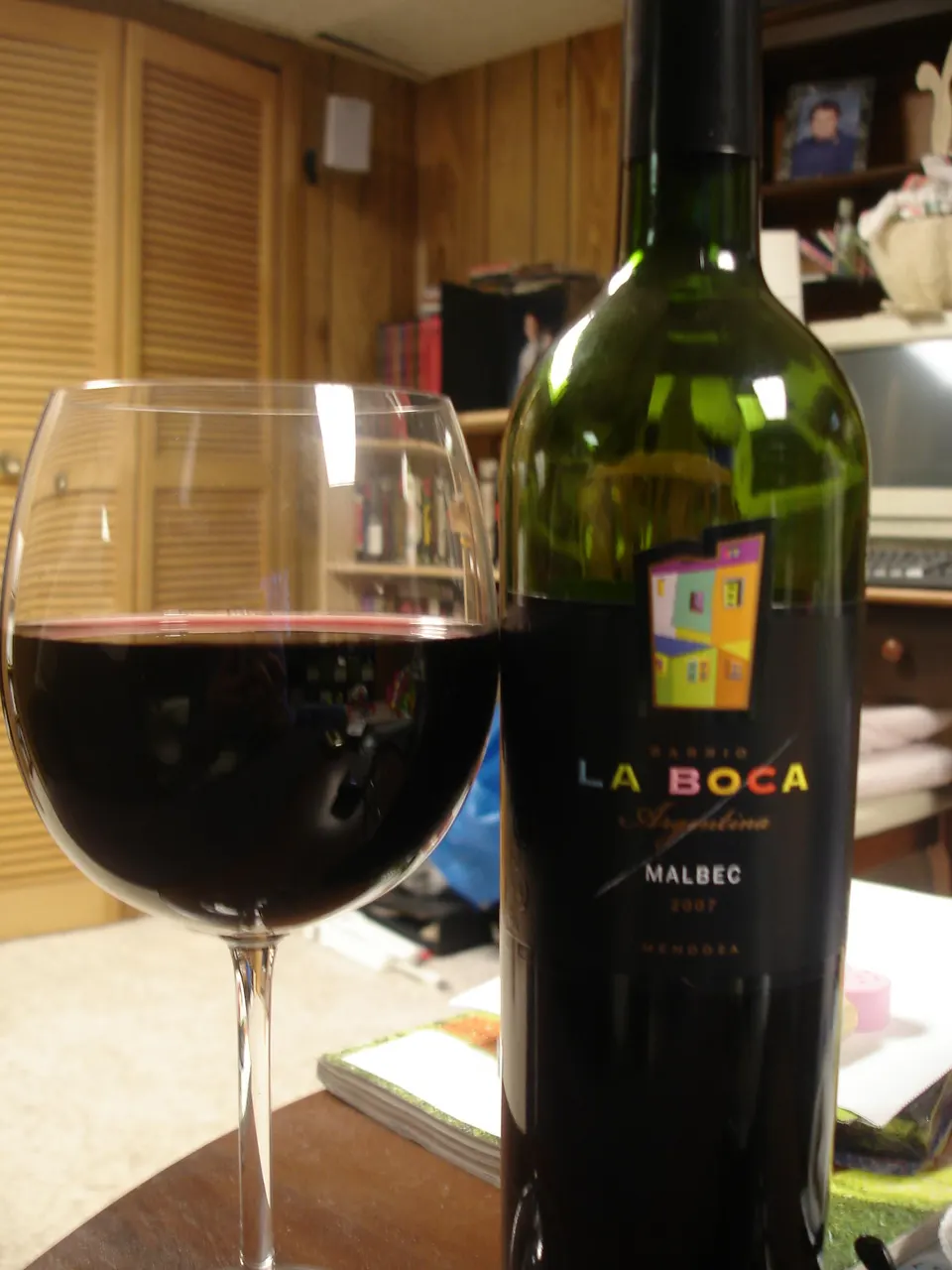 Copa de vino tinto Malbec mendocino servida frente a una botella en bodega.