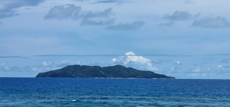 Vista costera de la isla privada de Castaway (Qalito) con aguas tranquilas y vegetación frondosa.