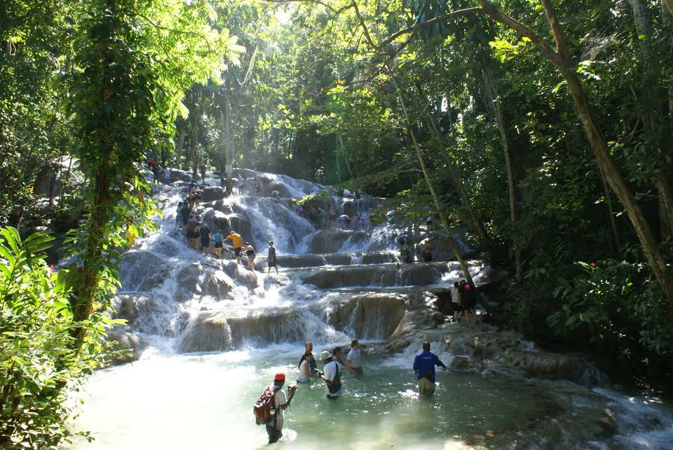 Turistas escalando tomados de la mano por las cascadas de Dunn's River Falls.