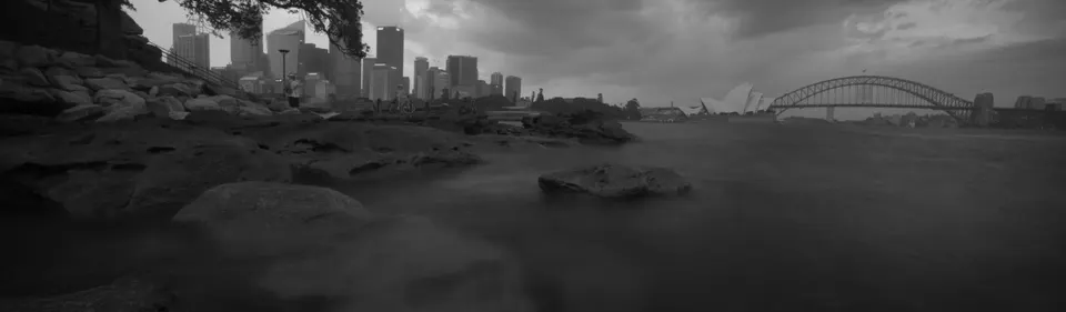 Panorámica clásica de la bahía de Sídney con la Opera House y el Harbour Bridge iluminados.