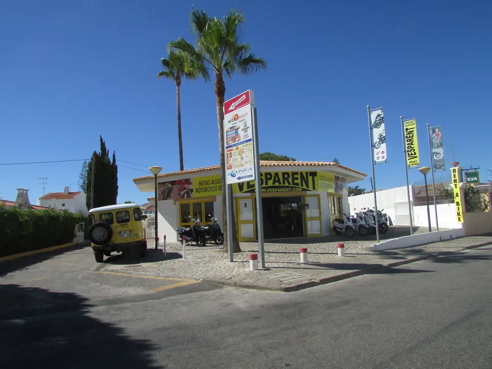 Hileras de motocicletas y scooters aparcados frente a una tienda de alquiler de vehículos para turistas.