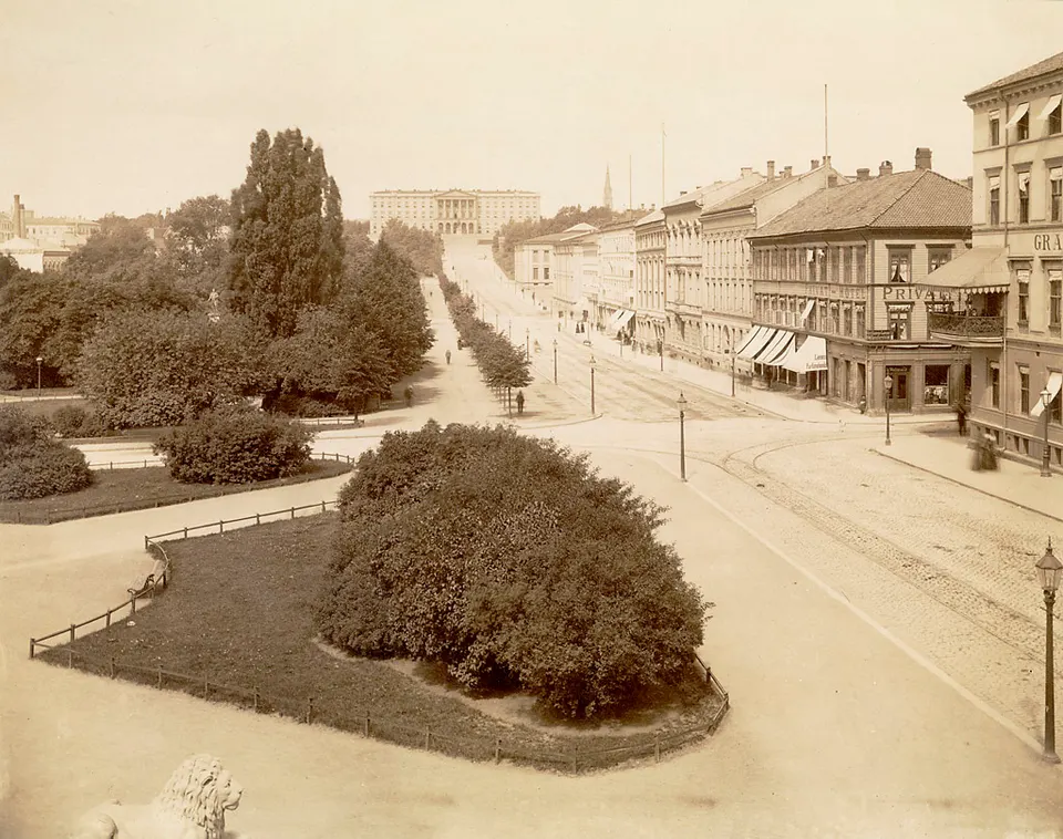 Avenida peatonal Karl Johans gate con arbolado y el edificio del Parlamento noruego (Stortinget).