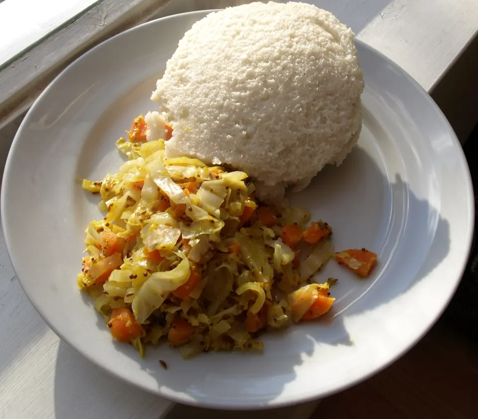 Plato tradicional de sadza de maíz acompañado de verduras salteadas y guiso aromático de carne.