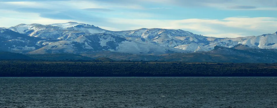 Aguas cristalinas y playas de montaña del Lago Nahuel Huapi frente a la cordillera.