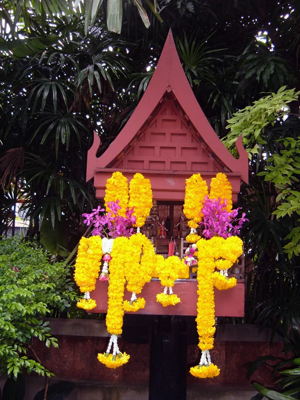 Arquitectura tradicional de teca tailandesa rodeada de exuberantes jardines tropicales en la Casa de Jim Thompson en Bangkok.