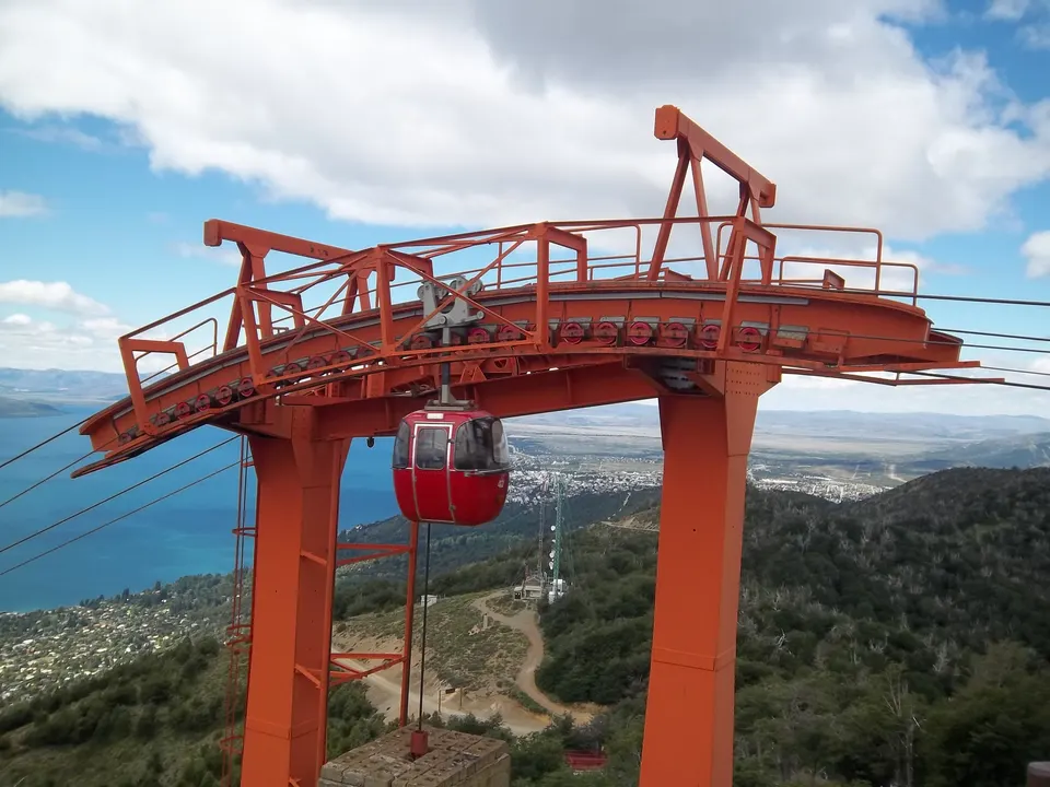 Góndolas rojas del teleférico del Cerro Otto ascendiendo sobre las laderas boscosas de Bariloche.