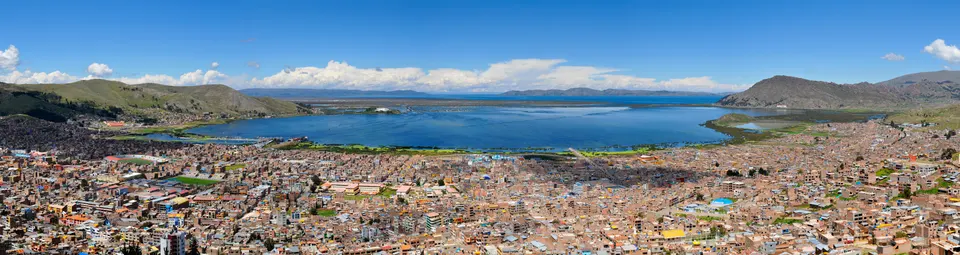 Aguas azul zafiro del Lago Titicaca a 3.812 metros de altitud frente al litoral de Puno con embarcaciones tradicionales
