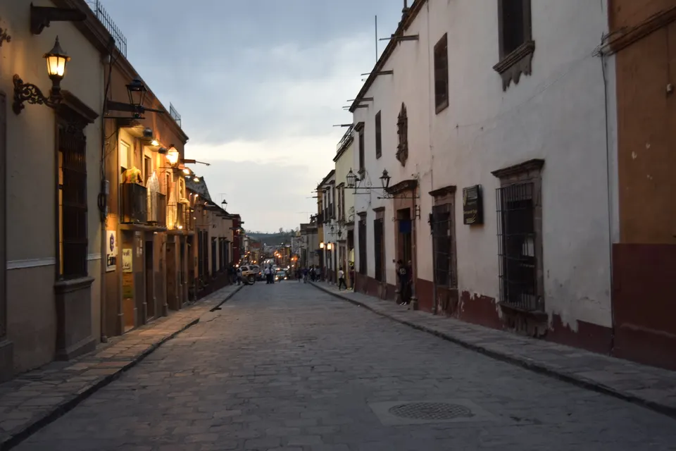 Calle empedrada tradicional con fachadas en colores ocre y terracota en San Miguel de Allende.