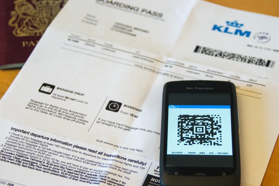 Tarjeta de embarque digital en pantalla de teléfono móvil junto a pasaporte de viaje.