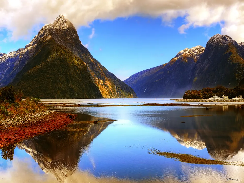 Paredes verticales de roca y el pico Mitre Peak reflejados en el fiordo de Milford Sound.