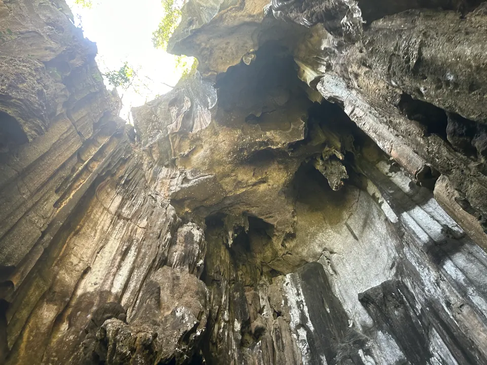 Techo de roca caliza y piscina natural iluminada por la luz solar en el interior de las cuevas de Sawa-i-Lau.
