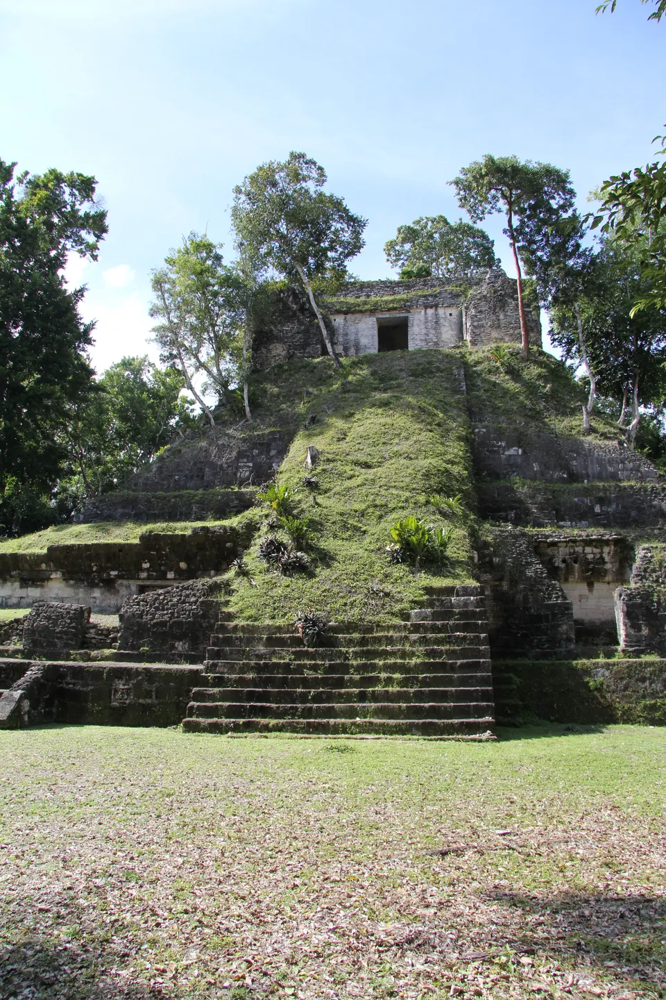 Pirámide maya del sitio arqueológico de Yaxhá elevándose frente a la laguna homónima en Petén.