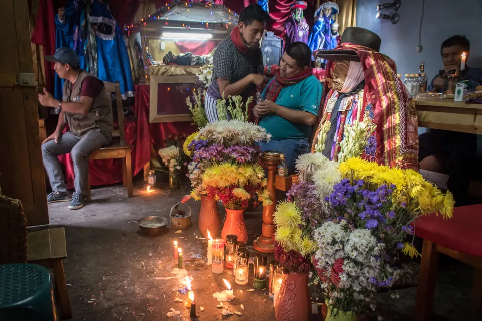 Efigie ceremonial de Maximón decorada con pañuelos de seda y ofrendas dentro de la casa de la cofradía en Santiago Atitlán.