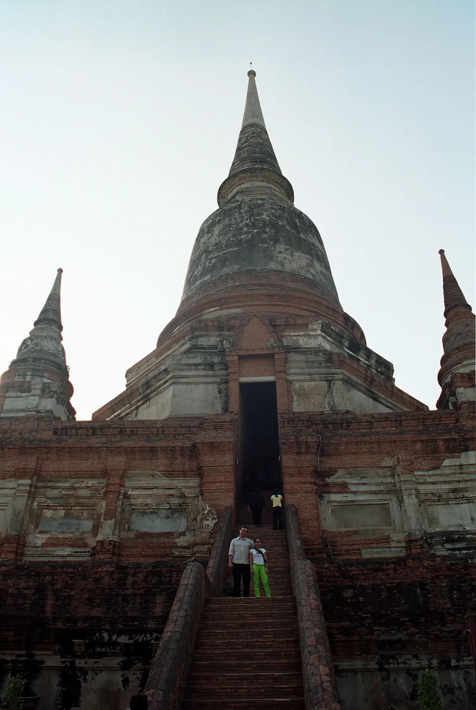 Colosal estupa chedi central y fila de estatuas de Buda vestidas con túnicas azafrán en Wat Yai Chai Mongkhon.